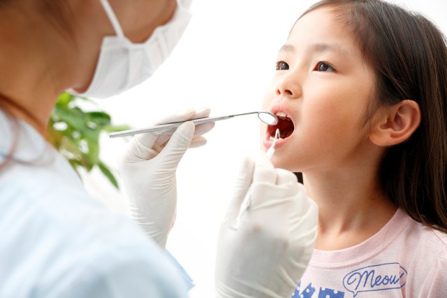 女の子の歯をチェックする歯科スタッフ